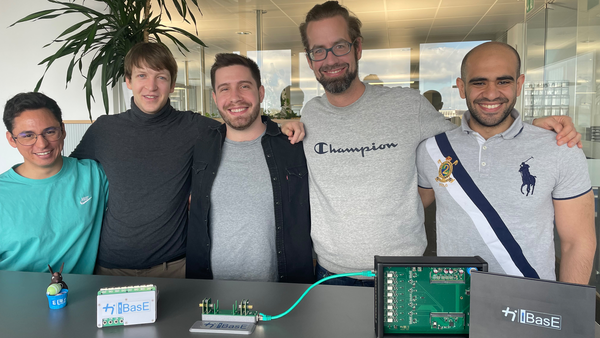 Five people stand in front of a desk witch a machine