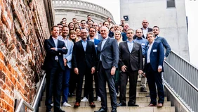 A group photo on a staircase, in the background parts of the brigk start-up center Ingolstadt.