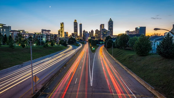 : A multi-lane road crisscrossed with colorful lines in the foreground, the skyline of a city in the background