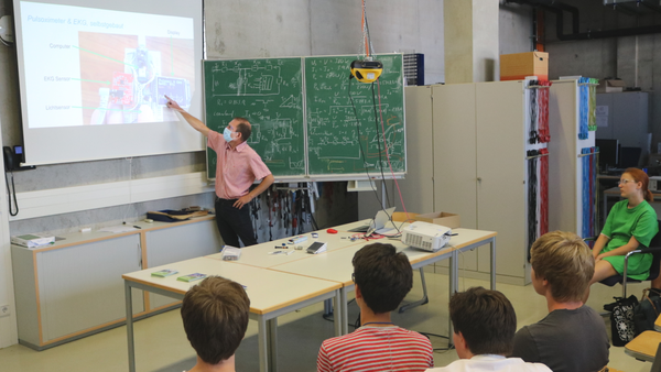 Professor points to the screen presentation in the lecture hall in front of the students