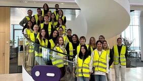 A group of young people wearing high visibility vests standing on a spiral staircase.