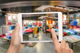 2 hands holding an IPad and taking a photograph of a shop