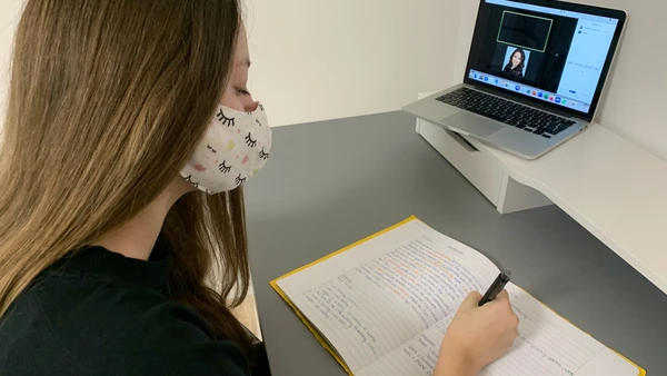 student sitting in front of her laptop taking part in a video conference