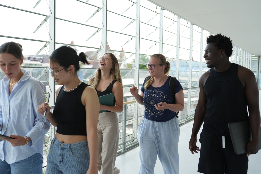 5 Studierende gehen in einem Gang der THI und sind glücklich