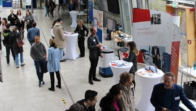 People in a foyer and at the exhibition stand